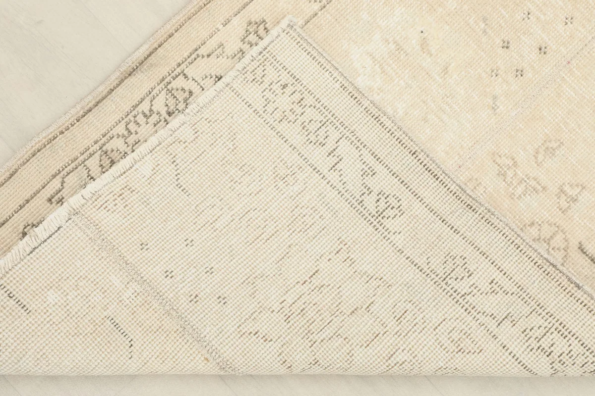 View of the back of the rug, folded to show the cotton foundation and hand-knotted construction