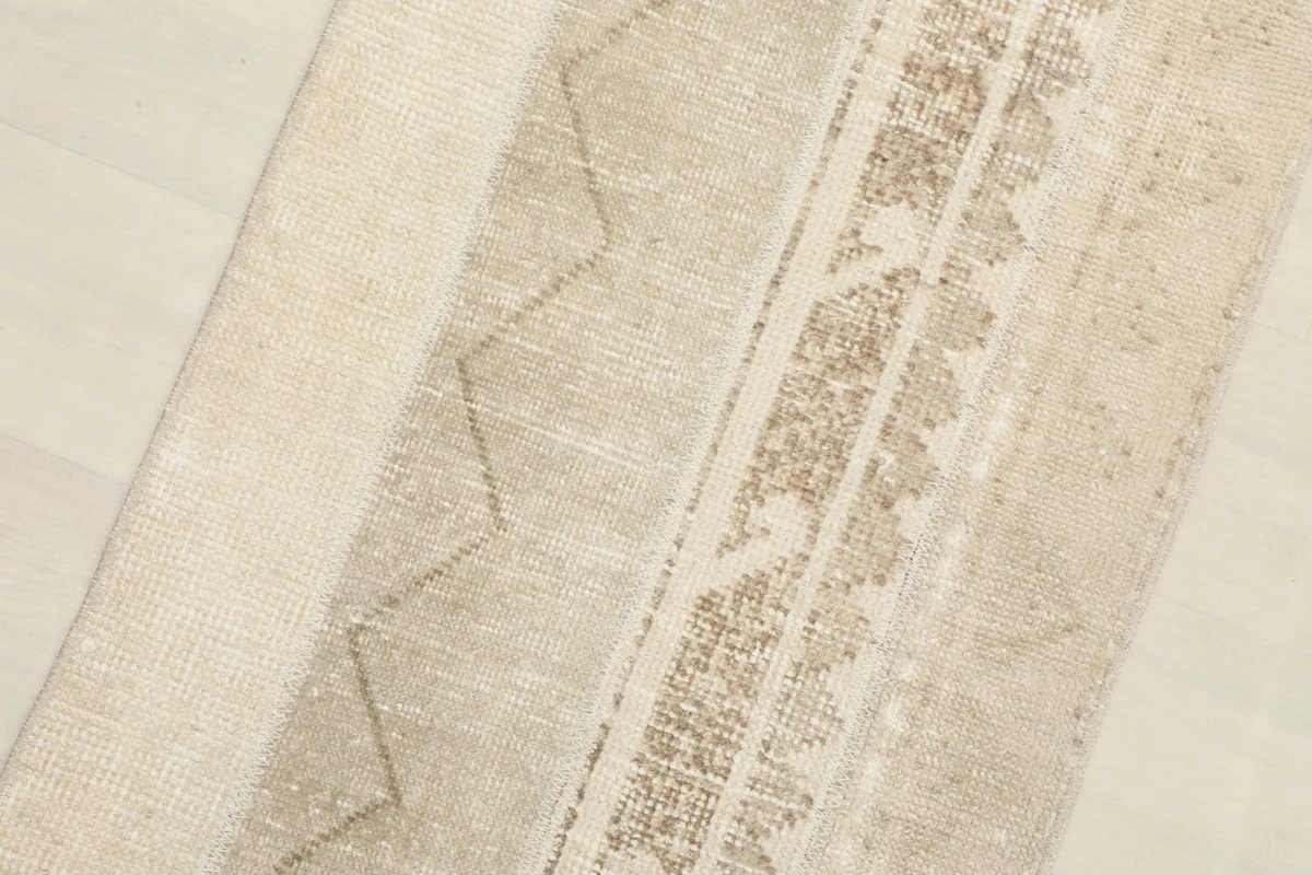 Close-up detail of the beige field and brown geometric and tribal patterns on the runner rug.