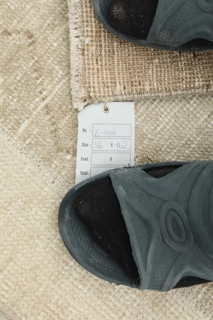 Close-up showing the rug's label with size information next to a shoe for scale.
