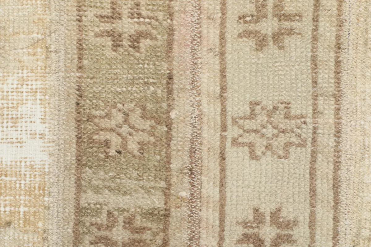 Extreme close-up of the hand-knotted wool pile and intricate brown and gray geometric designs