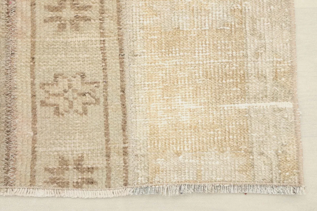 Detail of the rug's edge and fringe, showcasing the low pile and vintage wear