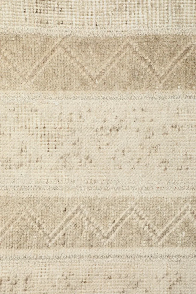 Extreme close-up of the low wool pile, showing individual knots and distressed areas.