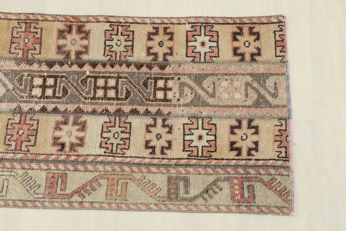 Close-up view of the rug's top section, highlighting geometric patterns in tan and rust