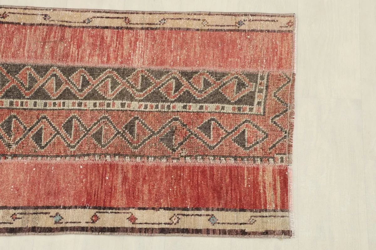 Close-up of one end of the rug, showing the intricate geometric patterns in charcoal, rust, and beige.