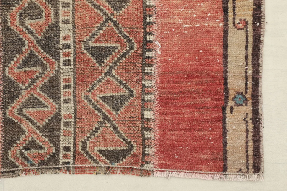 Close-up of the rug's side, showing the beige border with small decorative motifs and the red field.