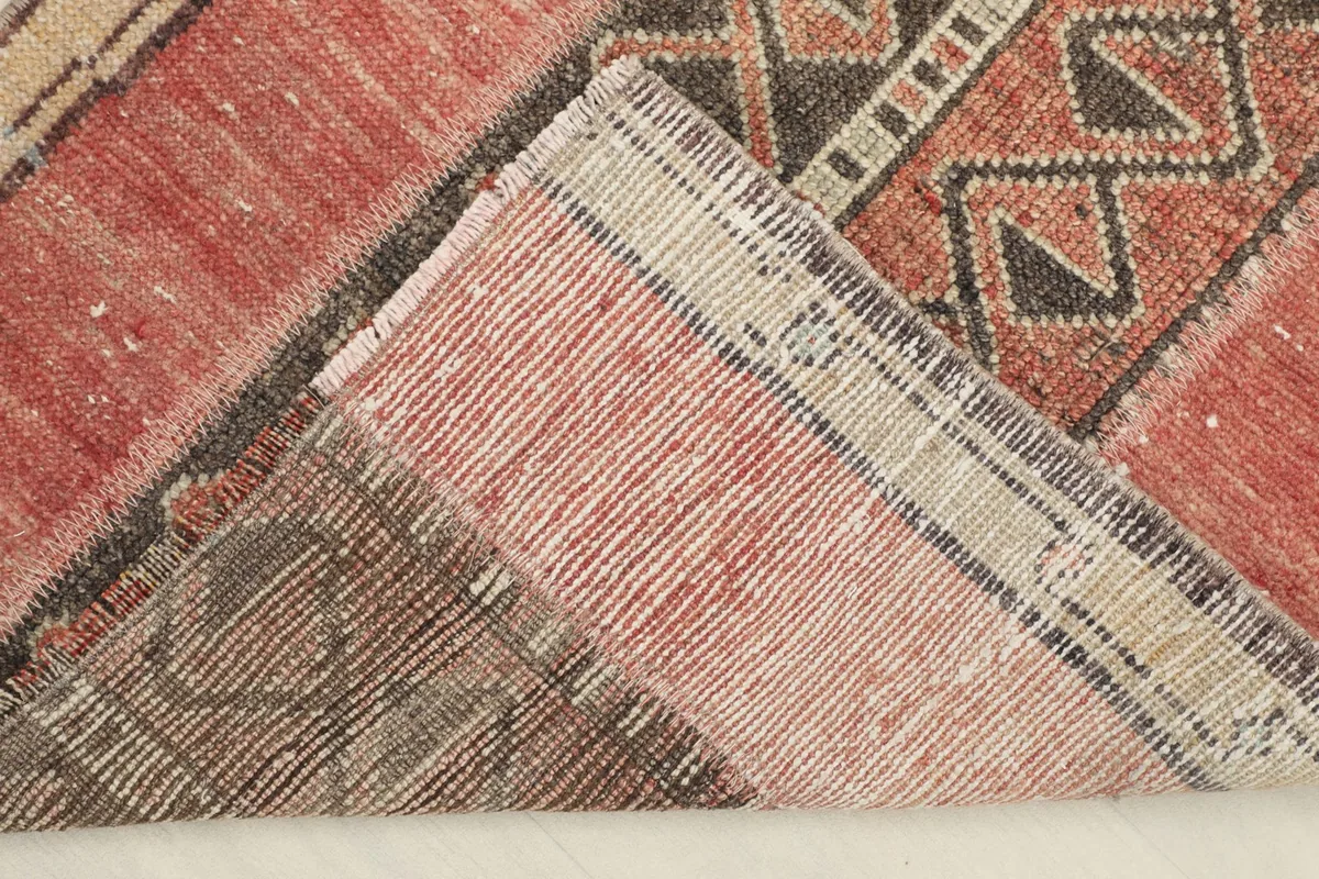 View of the back of the rug, folded to show the cotton foundation and the reverse of the hand-knotted pile.