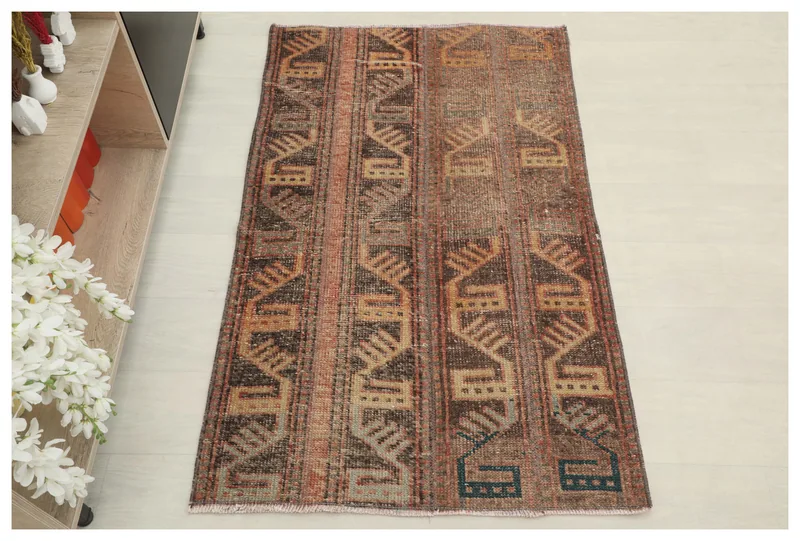Full top view of a 2'8" x 4'4" rustic brown geometric vintage Anatolian wool rug on a white floor.