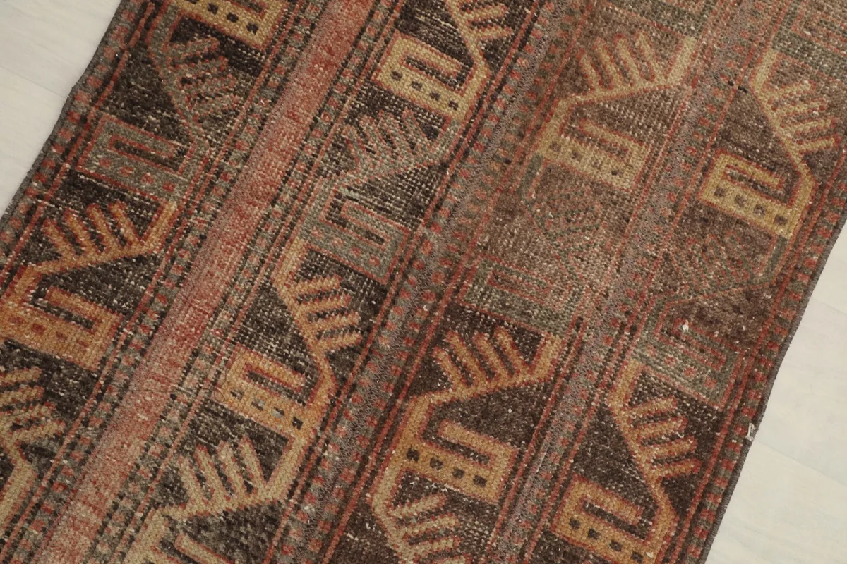 Close-up view of the rug's geometric motifs and color variations in brown, rust, and tan.
