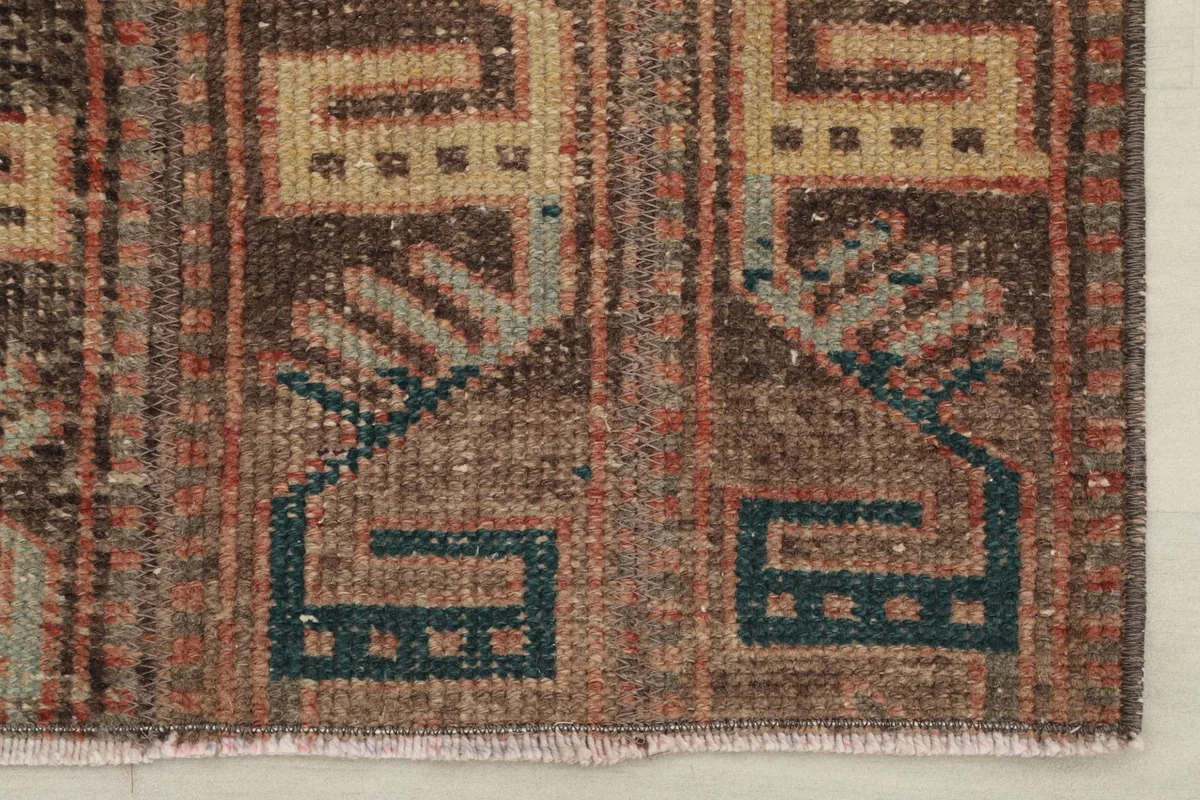 Detailed view of the rug's lower section, highlighting the blue-green accents within the patterns.