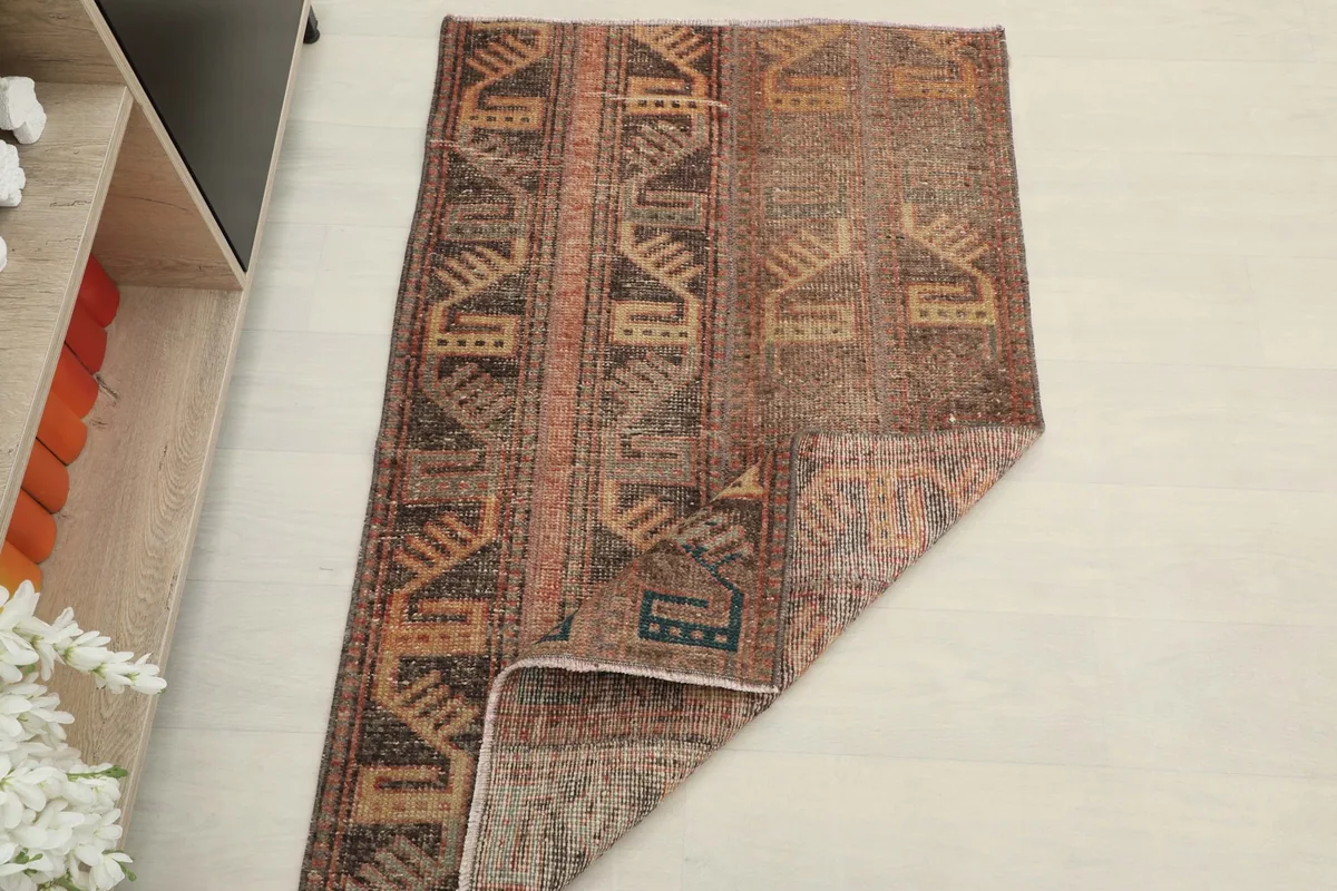 The rug partially folded, showing the flexibility and thickness of the vintage wool material.