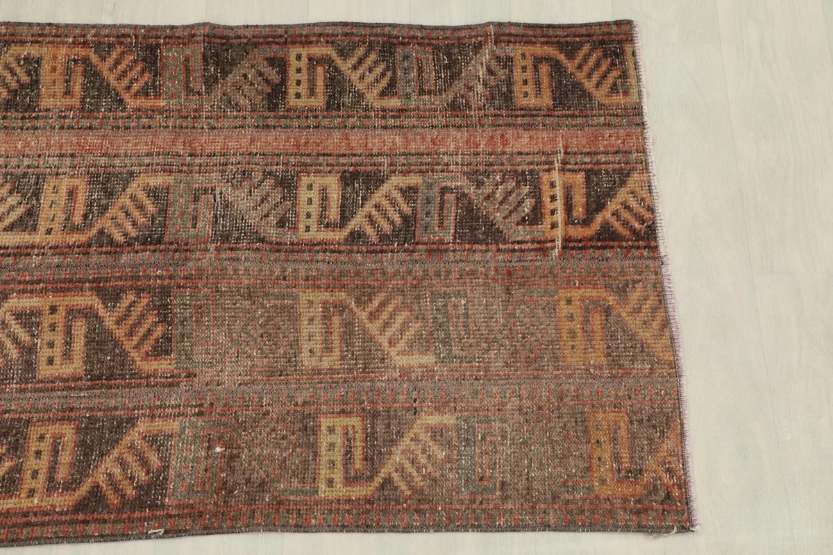 Overhead view of the rug's upper half, displaying the repeating geometric bands and muted colors.