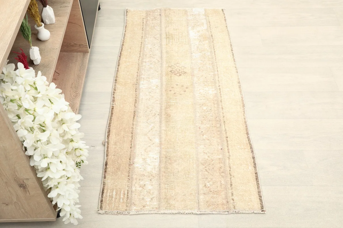 Overhead view of the beige and tan striped rug placed on a light floor next to a bookshelf.
