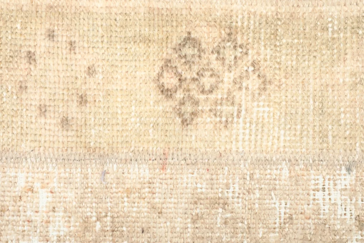 Detailed view of the faded geometric motifs and distressed appearance on the rug's surface.