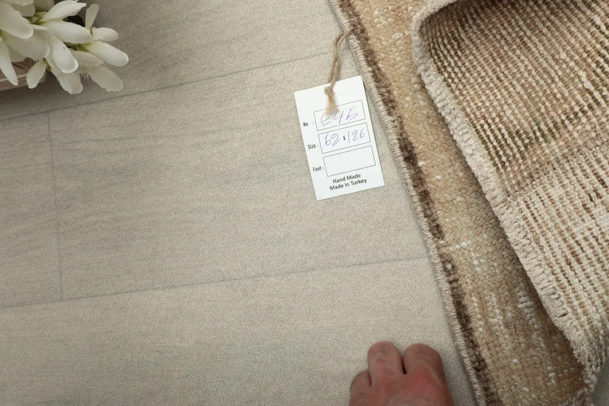 A rug tag on the floor next to the edge of the rug, indicating it is hand-made in Turkey.
