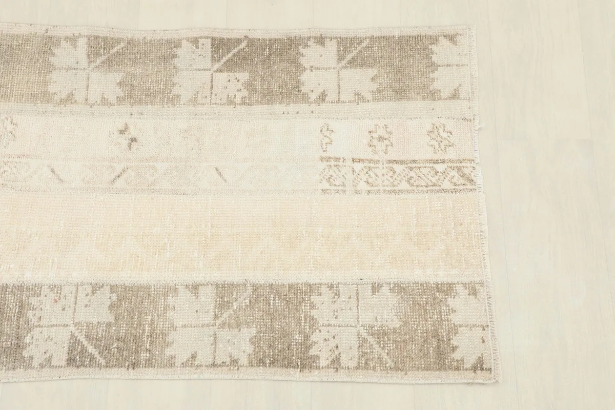 Close-up of the rug's top section, highlighting beige, cream, brown, and tan geometric patterns