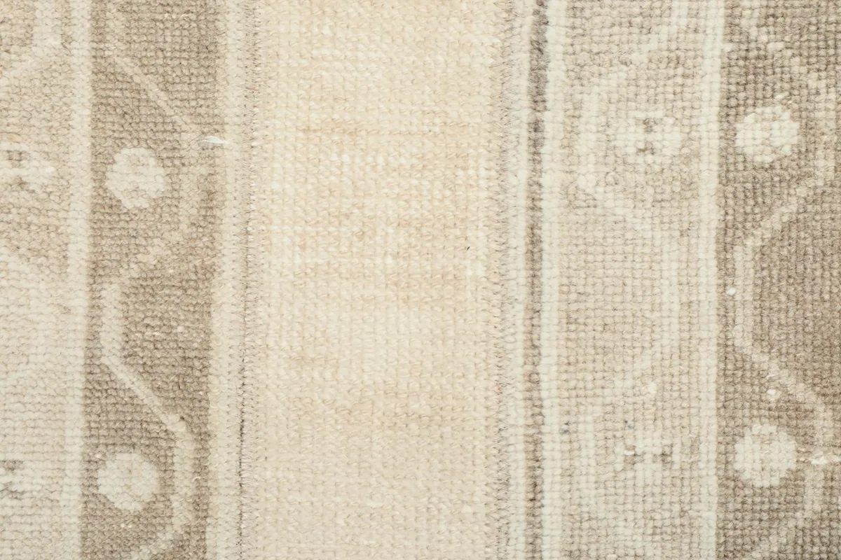 Close-up of the low wool pile and hand-knotted texture, showing the beige, tan, and gray yarn colors.