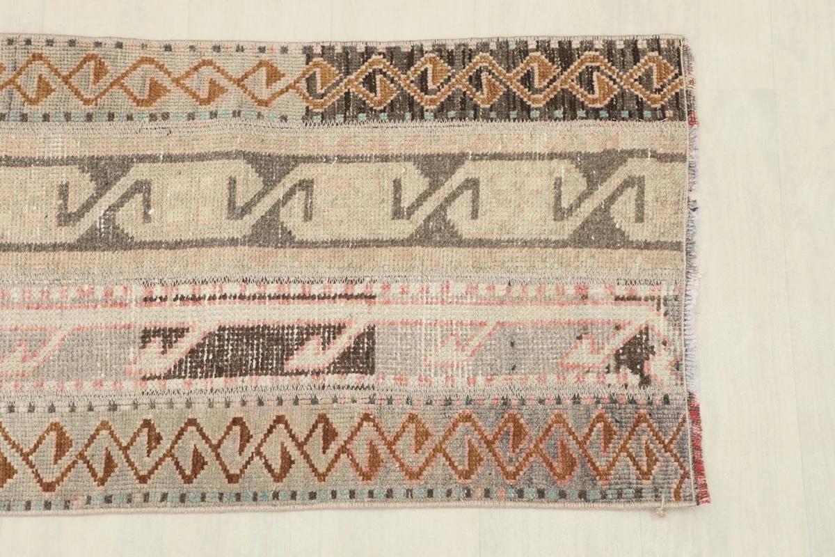 Close-up detail of the rug's patterns and colors, highlighting the beige, brown, and rust tones.