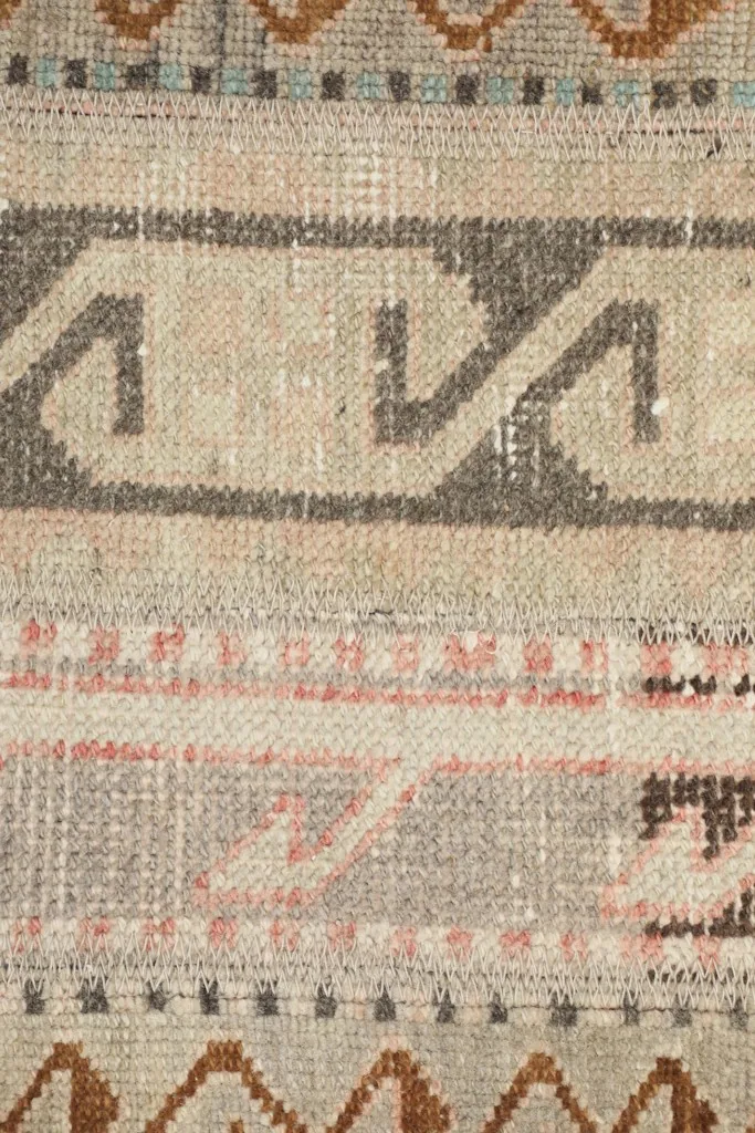 Macro shot of the rug's wool pile and cotton foundation, revealing the hand-knotted construction.