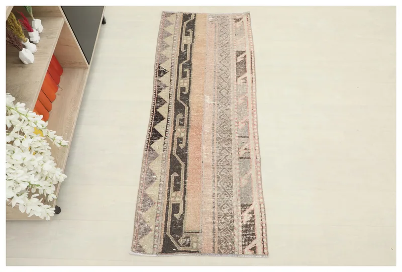 Full top view of the vintage rose, gray, and black geometric patchwork runner on a white background.