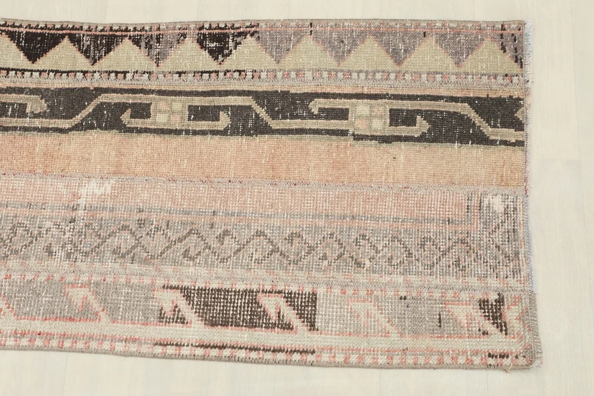 Close-up detail of the rose, gray, and black geometric patterns and textures within the runner.