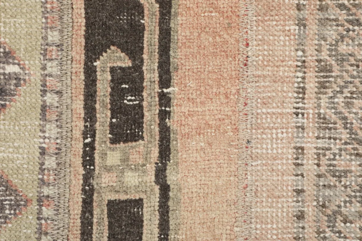 Detailed view of the low wool pile and the distinct rose and black geometric sections of the rug.