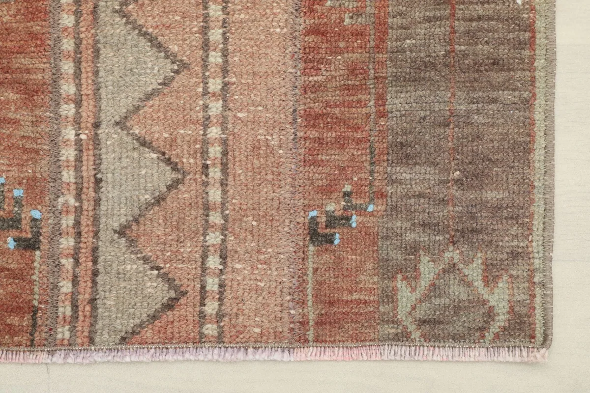 Detail of one end of the rug, showing the fringe and the edge of the woven pattern.