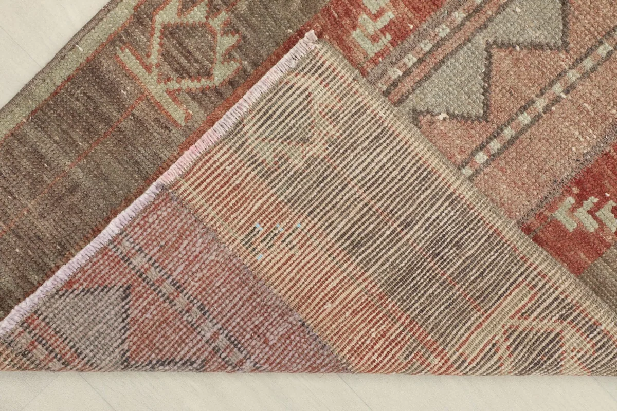 View of the back of the rug, folded to show the cotton foundation and knotting structure.