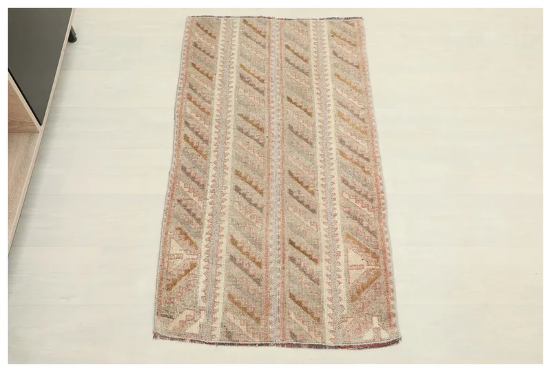 Full top view of the beige and rose geometric vintage Anatolian rug on a white floor.