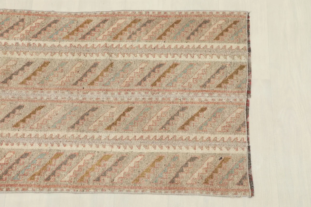 Close-up of the rug's edge, highlighting the striped geometric pattern and muted colors.