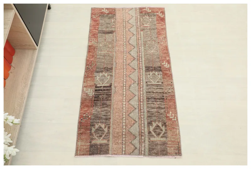 Full overhead view of the 2x4 rose and brown geometric vintage Anatolian area rug on a white background.