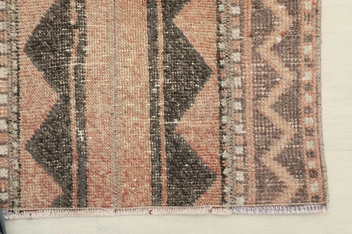 Close-up of the rug's edge, revealing the subtle fringed finish and patterned border.