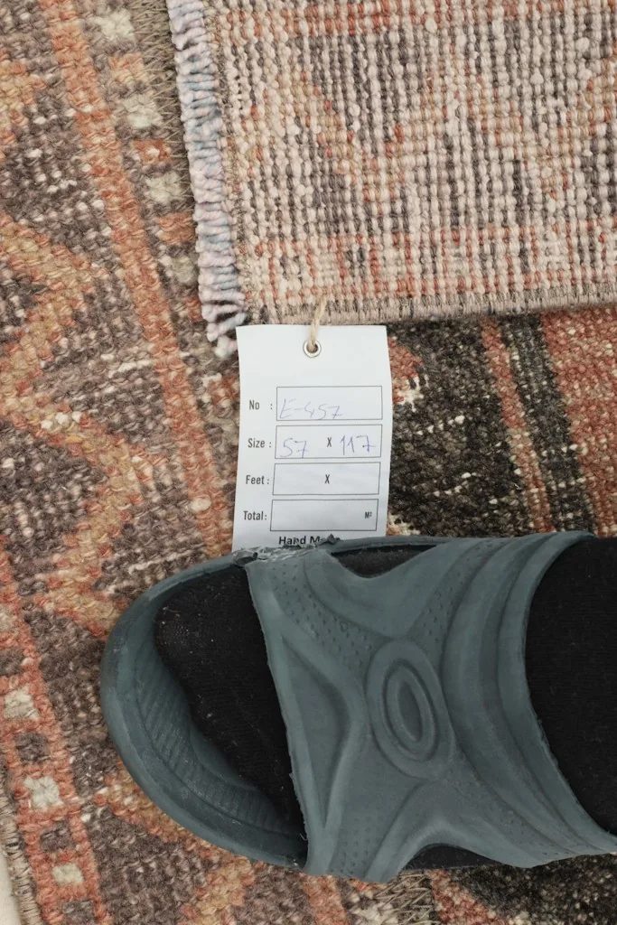 Detail of the rug's texture and a size tag, providing a sense of scale with a sandal.