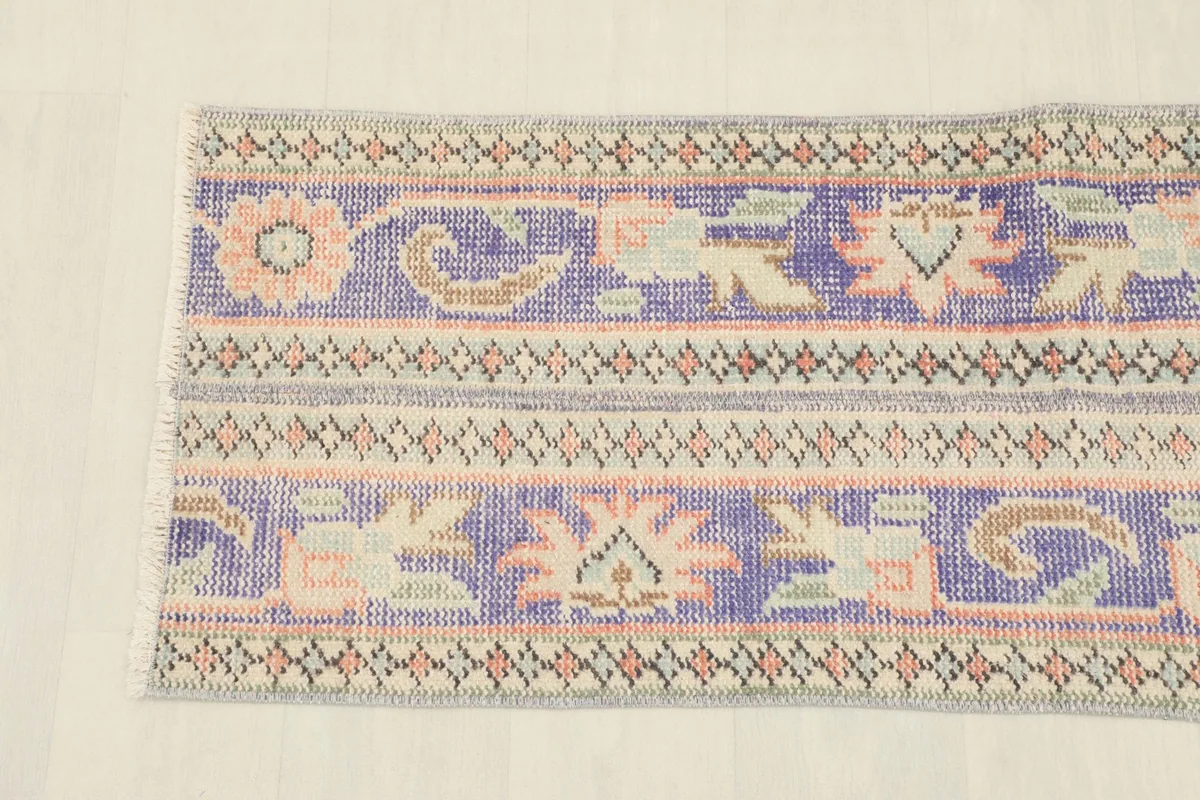 Detailed view of the rug's patterns, highlighting the blend of purple, beige, rose, and green colors.