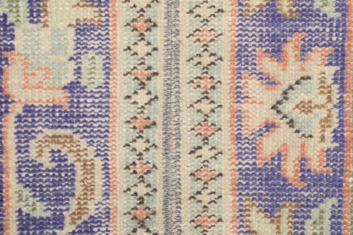 Close-up of the low wool pile, revealing the intricate hand-knotted texture and color variations.
