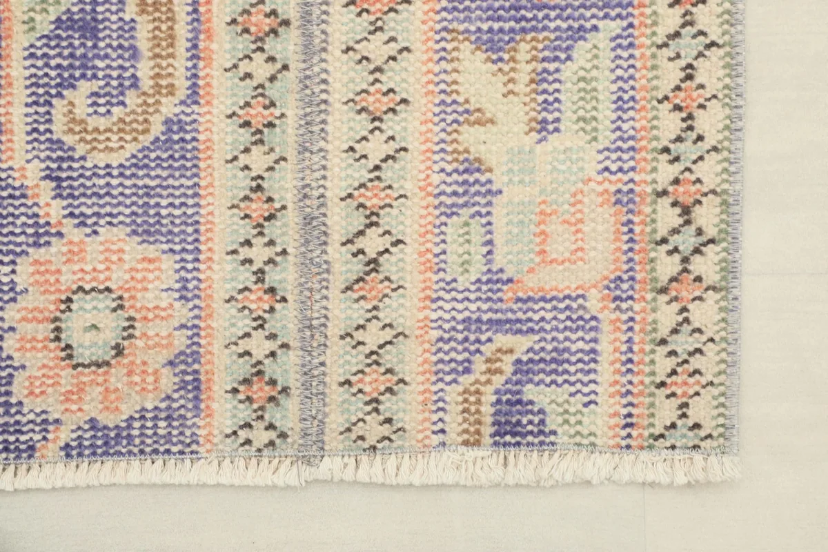 Detail of the rug's end, showing the short, natural fringe and the patterns near the edge.