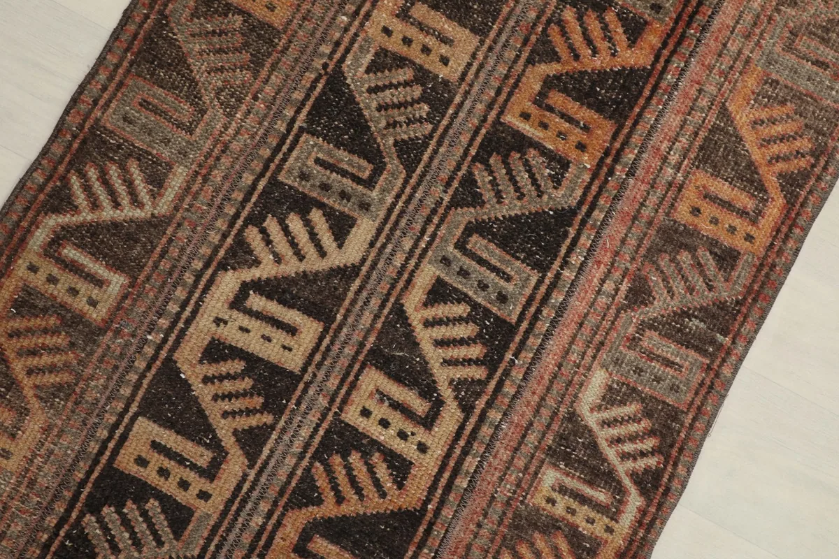 Close-up detail of the rug's geometric and tribal patterns in brown, charcoal, and tan