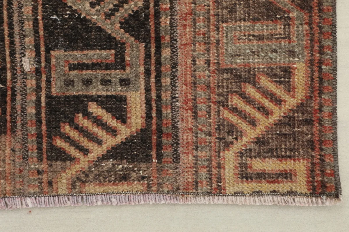 Corner detail of the rug, showing the fringe and edge with geometric designs