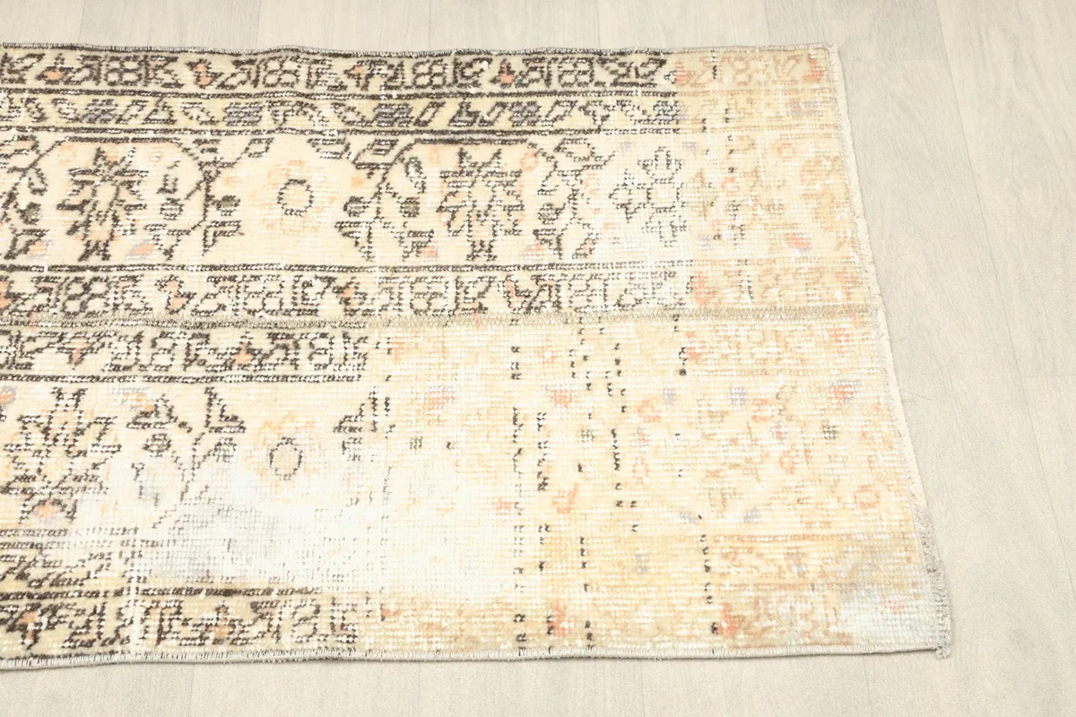 Angled top view of the rug's right side, revealing the faded areas and the overall distressed appearance.