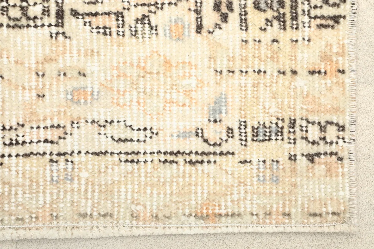 Close-up detail of the rug's short fringe and subtle color variations, including orange and blue accents.