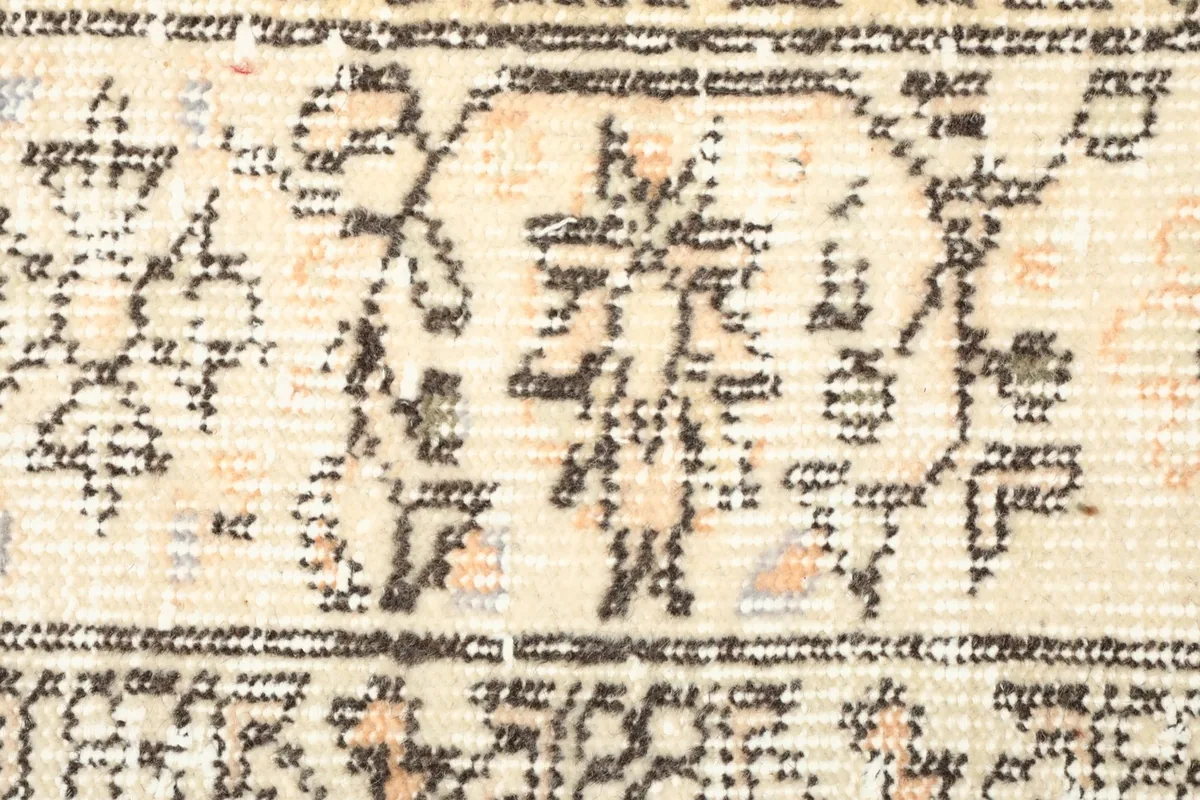 Detailed view of the brown geometric patterns and the low pile, showing signs of honest wear.