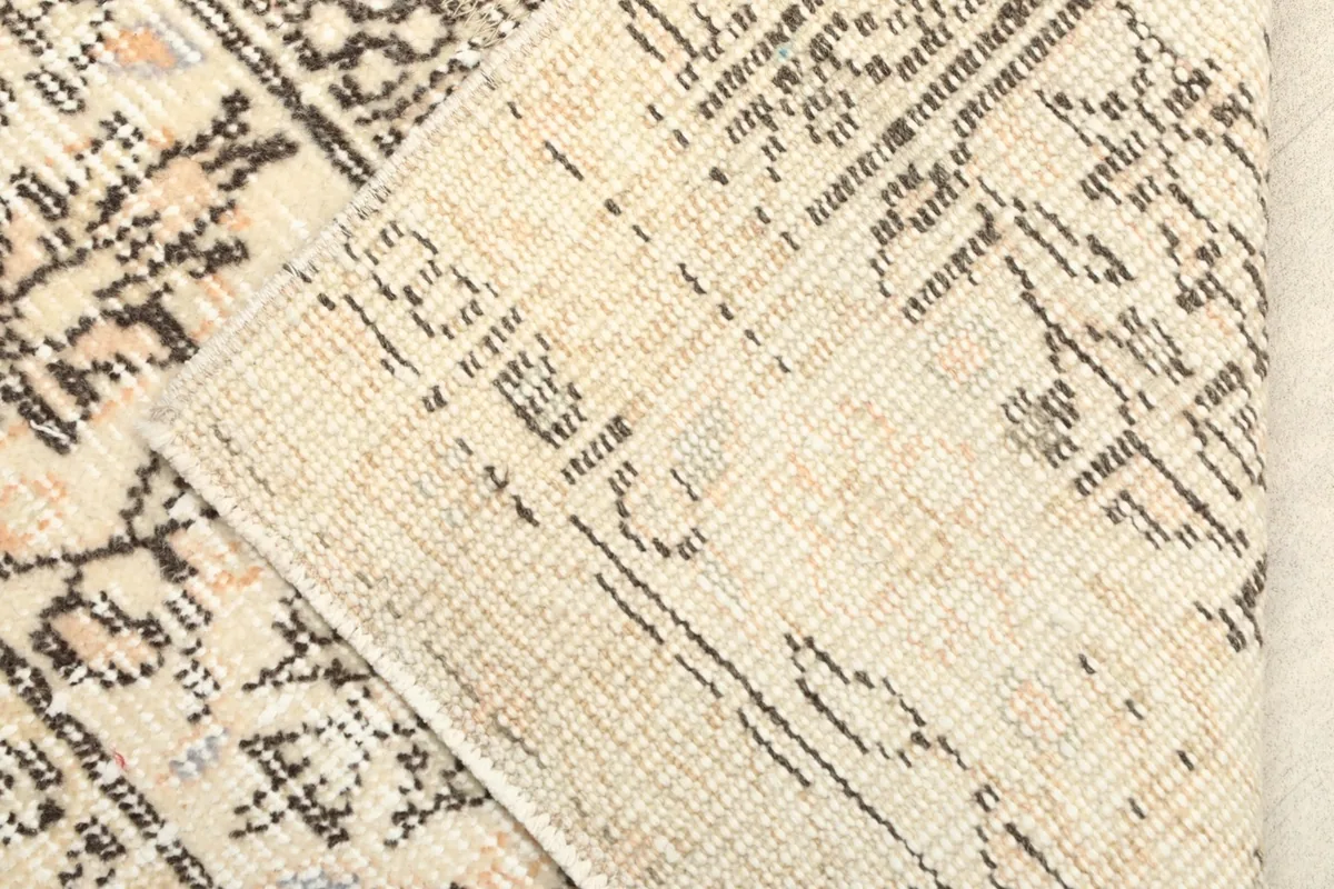 Close-up showing the low wool pile and the hand-knotted construction from a folded corner.