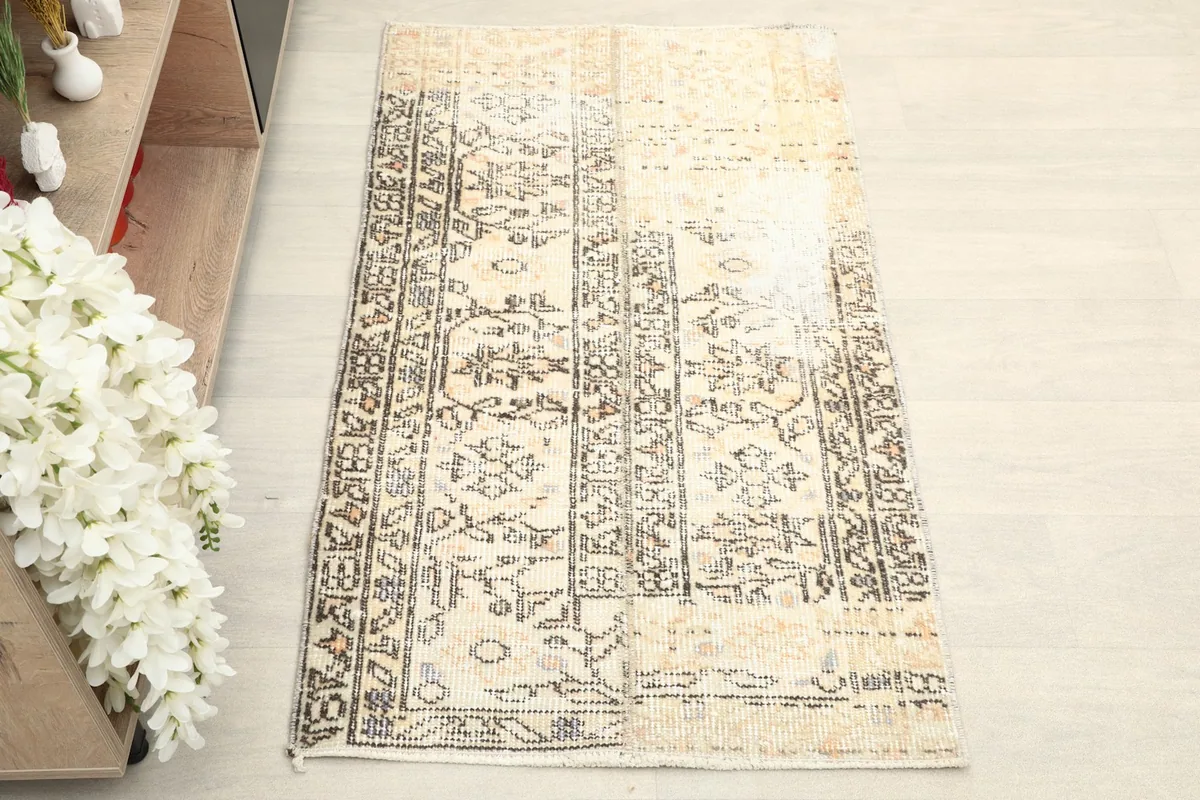 Overhead view of the beige rug, showcasing its brown geometric and floral patterns and faded character.