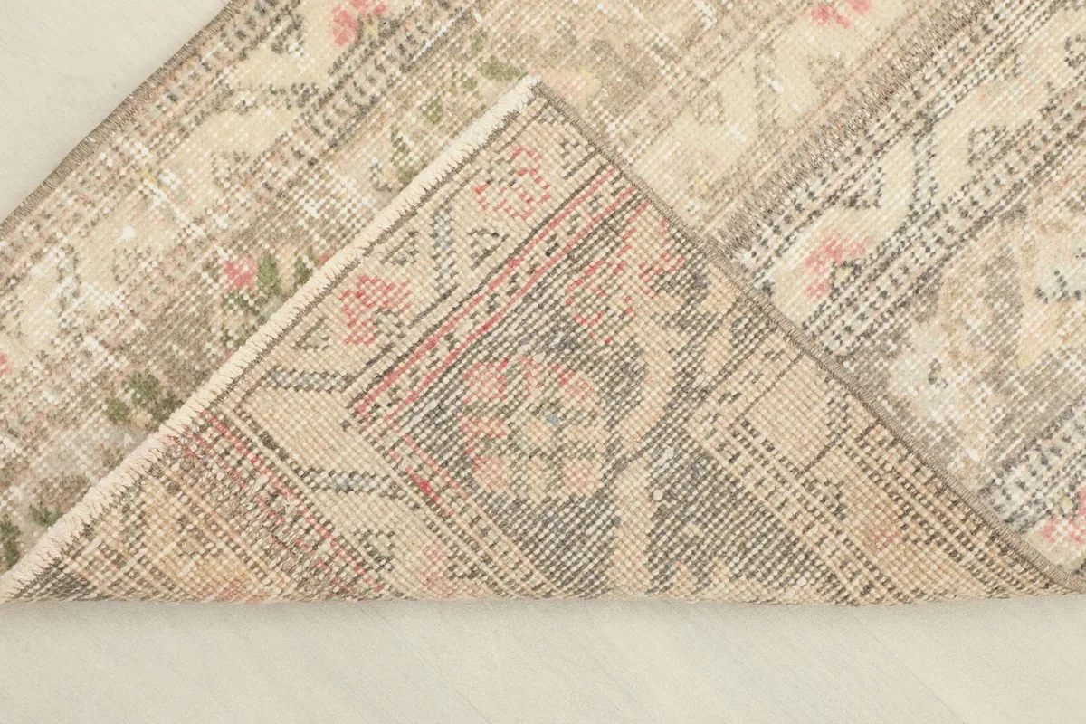 Folded corner revealing the cotton foundation and the reverse side of the hand-knotted rug.