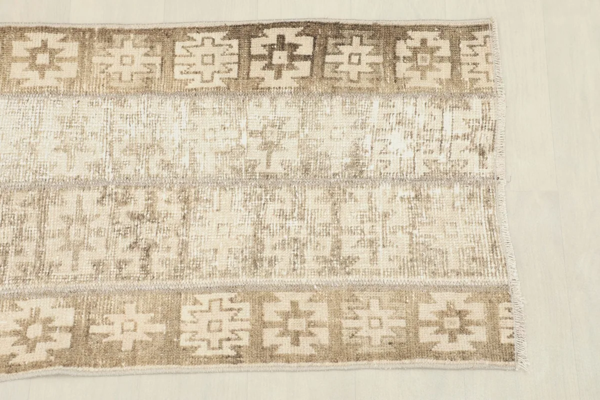 Close-up detail of the rug's central field and border, highlighting the beige and brown geometric motifs.