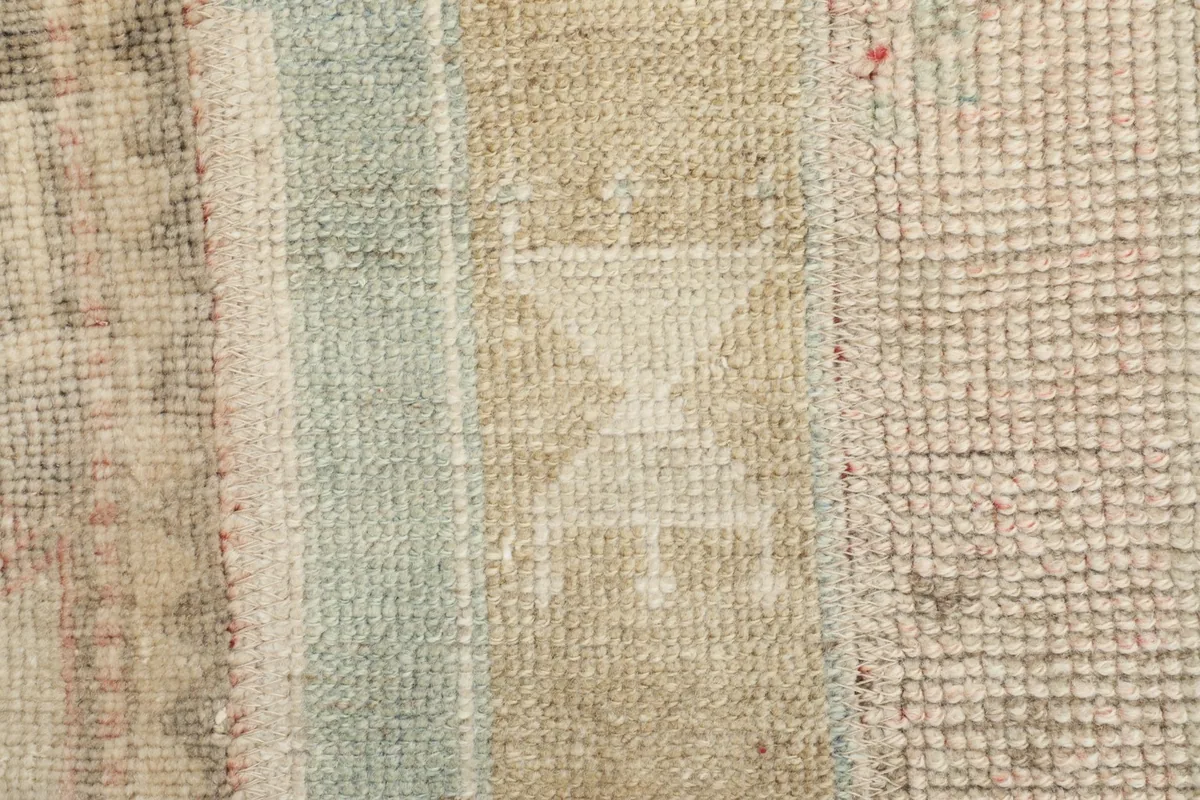 Detailed close-up of a central geometric motif and the subtle color shifts in the low pile of the rug.
