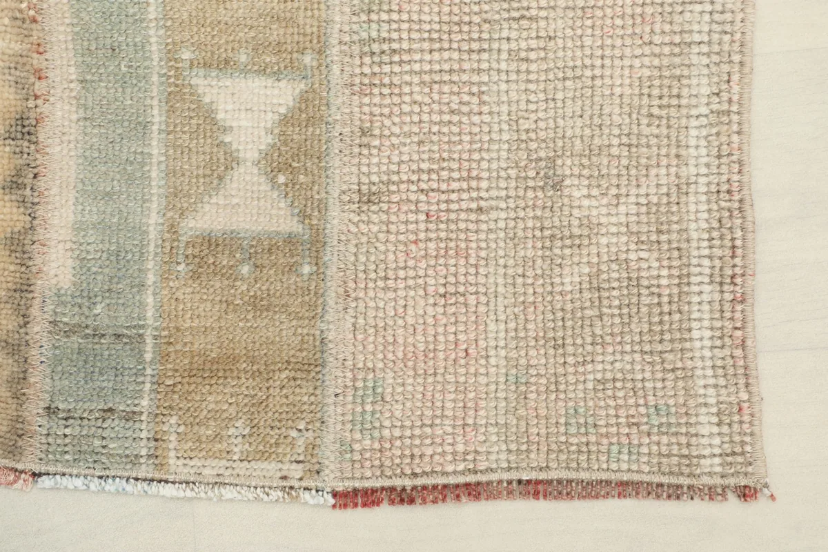 Close-up view of the low wool pile and the hand-knotted texture, showing minor wear consistent with its vintage nature.