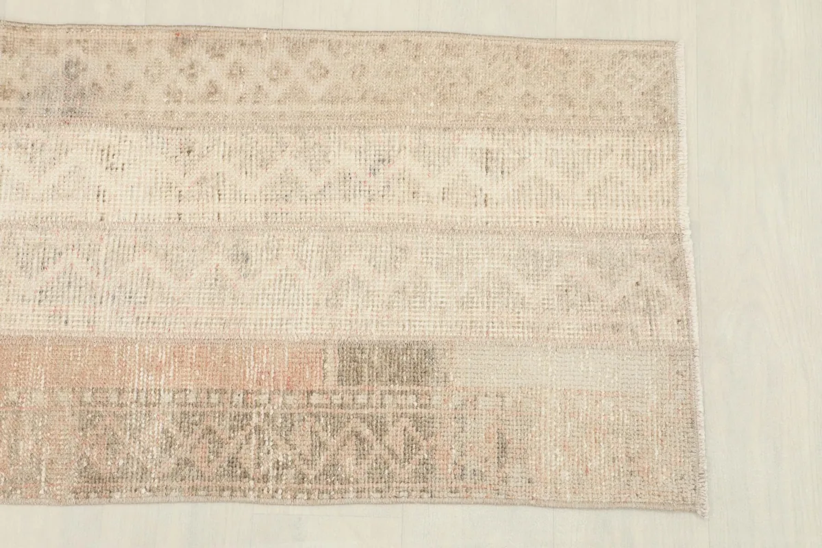 Close-up of the rug's surface, highlighting the various beige, tan, and cream striped panels and motifs.