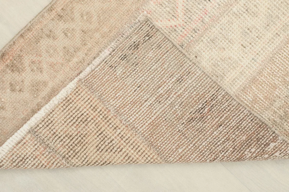 View of the back of the rug, folded to show the hand-knotted cotton foundation.