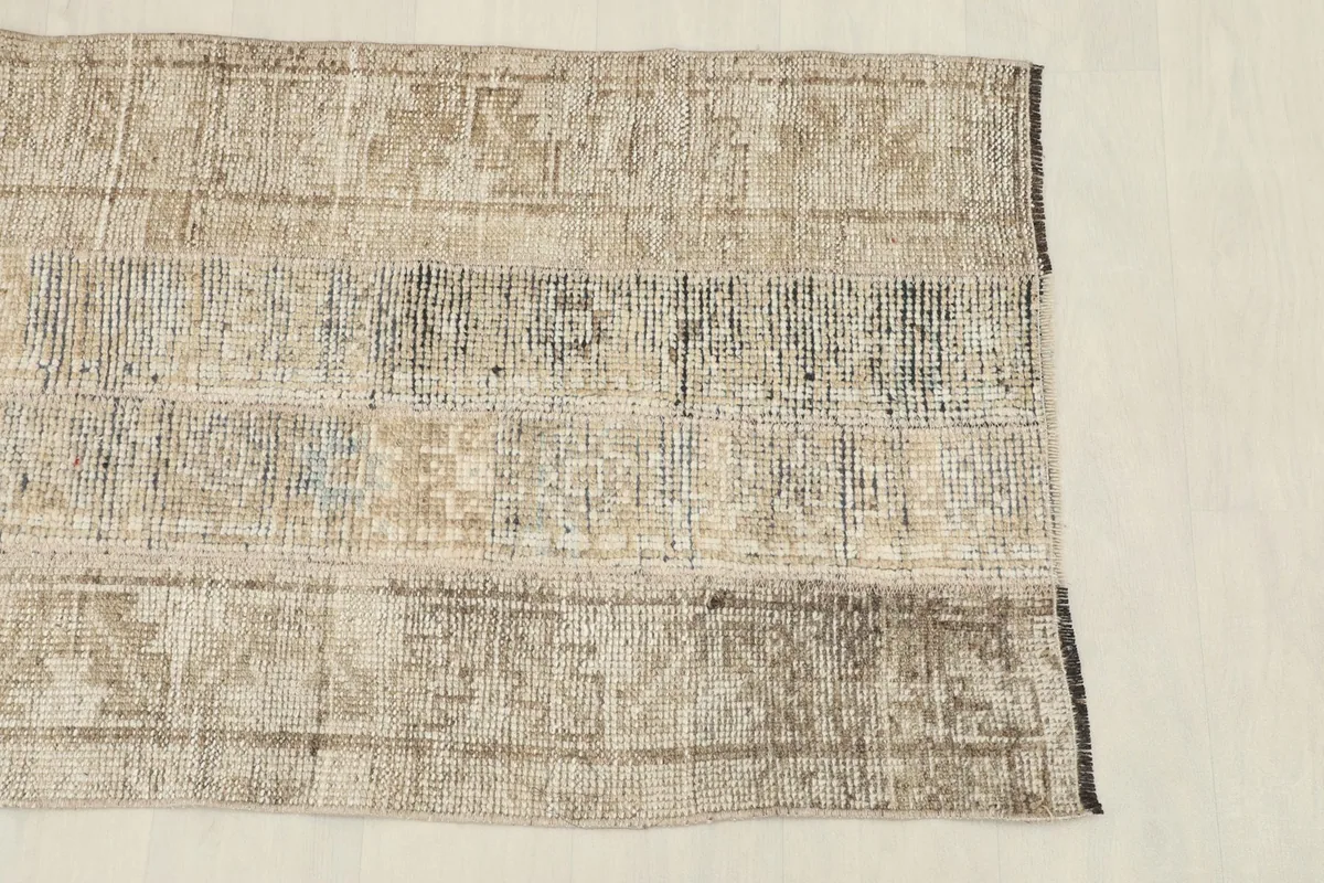 Close-up of the rug's surface, highlighting the various beige, brown, and gray patches with tribal motifs.