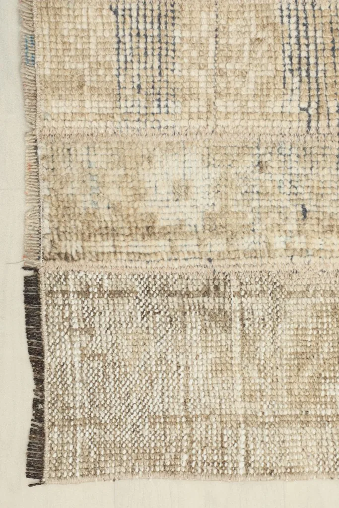 View of the rug's edge, showing the tightly woven cotton foundation and the short, dark fringes.